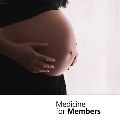 The lower half of a pregnant woman with her hands on her bump