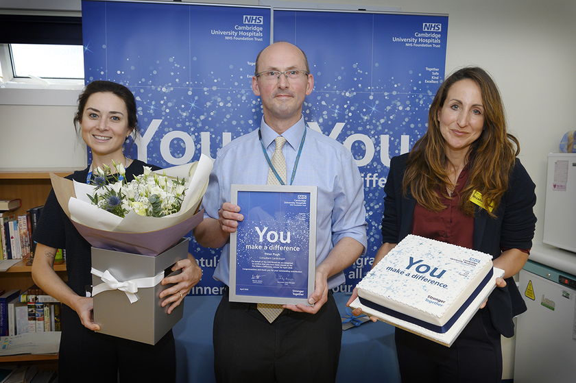 Peter Pugh with Nicola Ayton and Beth holding a certificate, flowers and cake