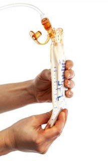 a clear laboratory separation funnel with blue volume markings. The funnel contains a small amount of red liquid pooled at the pointed bottom and is fitted with amber-colored stopcocks and attached clear tubing at the top