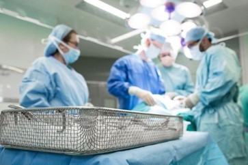 Surgical team in blue scrubs performing an operation in an operating room.
