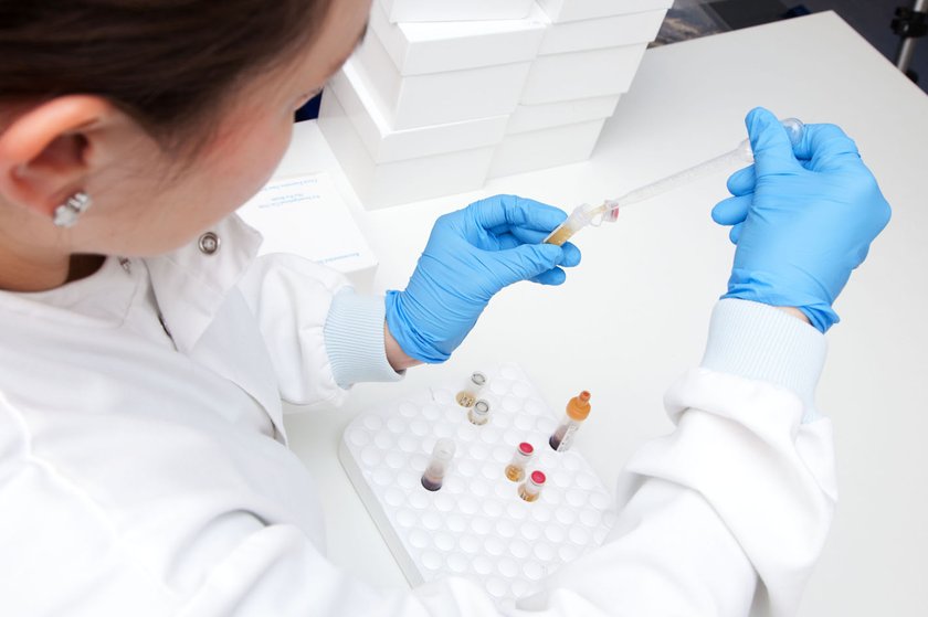 A scientist using test tube/ pipettes