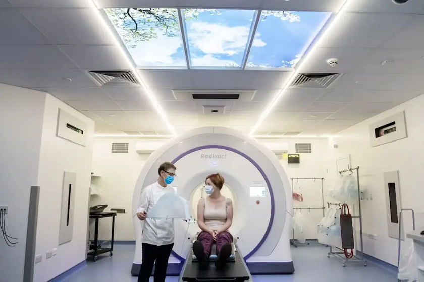 A woman on an MRI machine with a staff member beside her