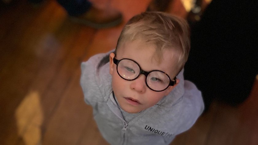 Little boy with glasses looking up at the camera