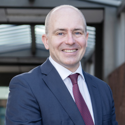 A man in a suit smiling outside Addenbrooke's hospital