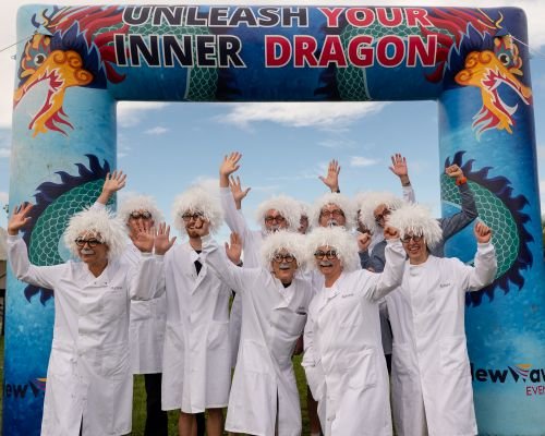 A group of women and men dressed as man professors, in white lab coats with white afro hair and moustaches
