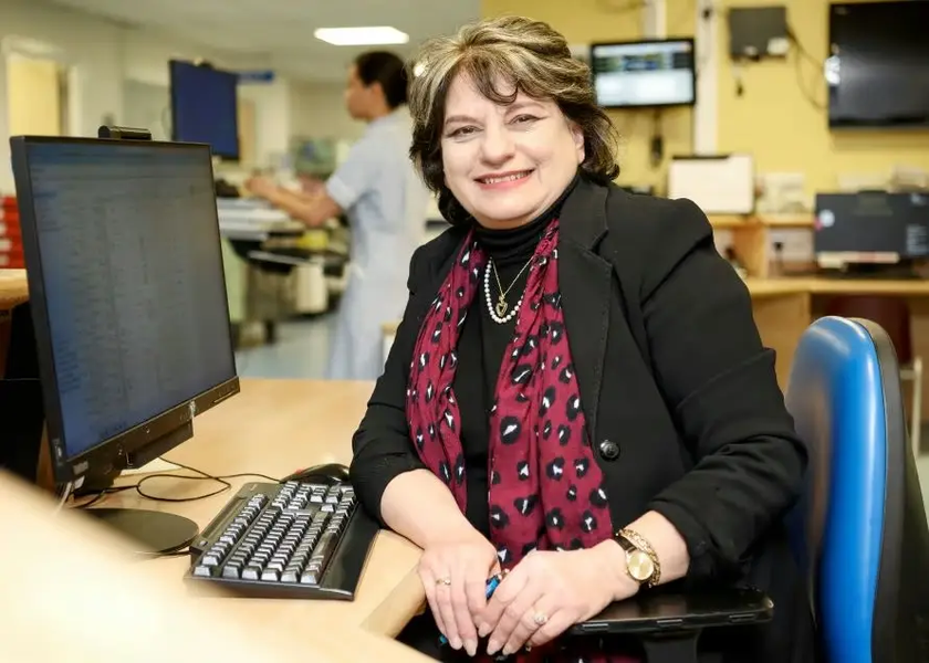 Sahar Majid sitting at a desk, facing the camera and smiling