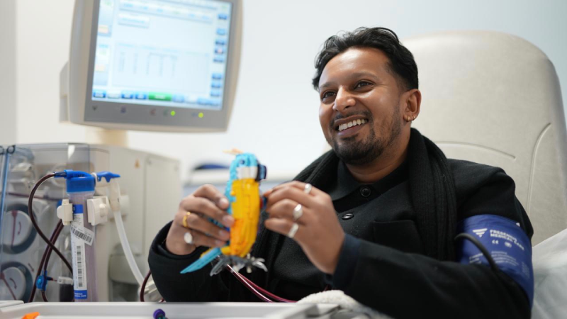 Sameer sitting in front of his haemodialysis machine building a brightly coloured lego parrott