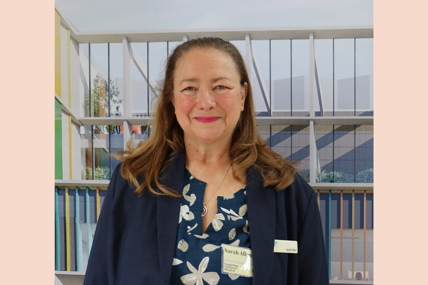 A woman with long brown hair, a smart black jacket and flowery top