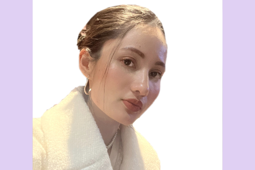 A woman with very dark brown hair tied back. She is wearing a fluffy cream coloured jacket