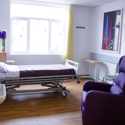 A room in ward T2 including a bed and armchair. On the wall and windows are large decorative stylised prints of flowers.