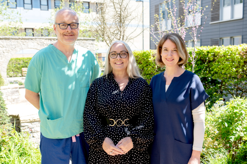 Victoria standing between Mr Wheeler and Ms Bolton, her surgeons, in a sunny garden