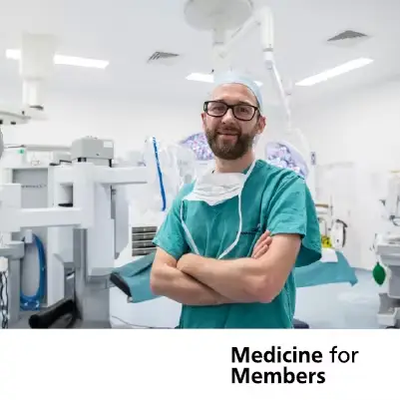 Grant Stewart standing in an operating theatre in scrubs. Text below reads 'Medicine for Members'