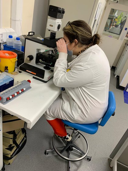 A photograph of a woman looking into a microscope