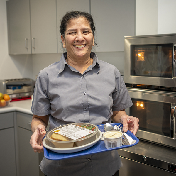 Savi Patel holding a tray with food for a patient on it