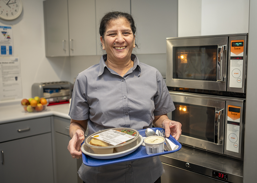 Savi Patel holding a tray with food for a patient on it