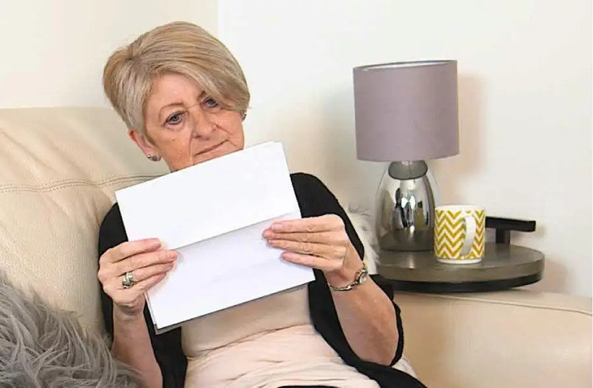 Person sat on sofa reading a hospital appointment letter.