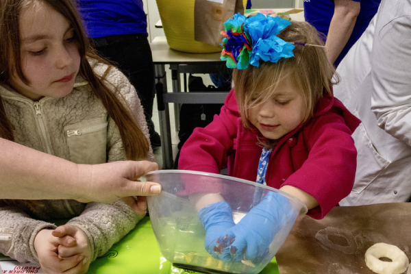 A child wearing gloves in a plastic bowl doing a hands-on activity