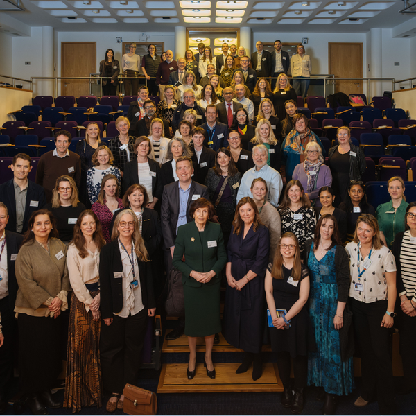 A large group of people in an auditorium at a conference smiling at the camera.