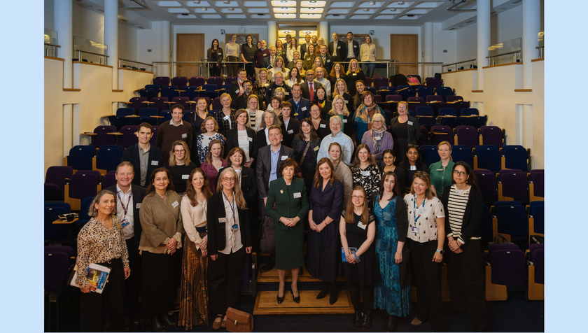 A large group of people in an auditorium at a conference smiling at the camera.