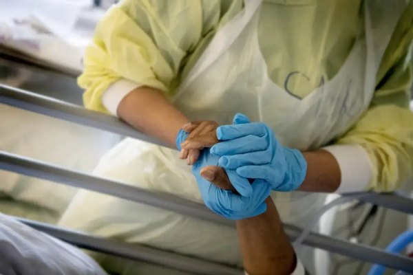Hands with blue gloves on holding a patients hand