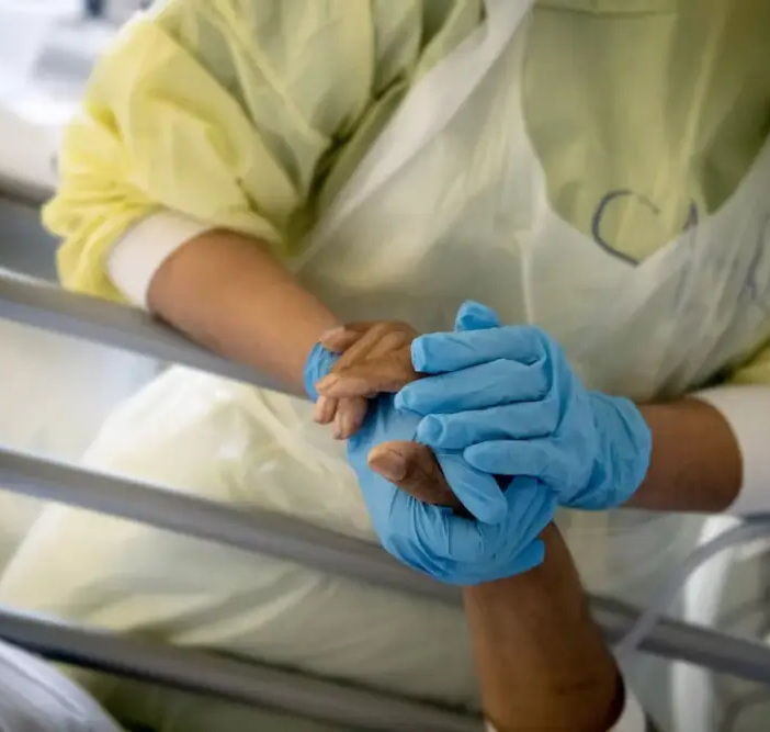 Hands with blue gloves on holding a patients hand