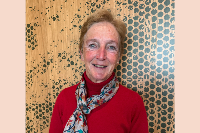 A woman with short reddish brown hair, a red jumper and patterned scarf