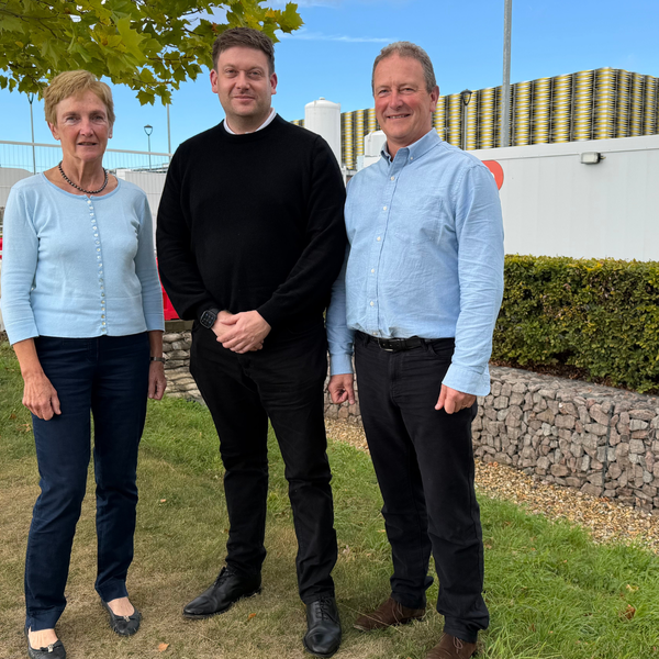 A woman and two men standing by the Cambridge Children's hospital collaboration hub, which is a white portacabin on the construction site