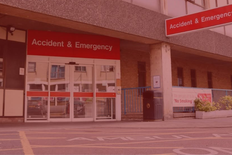 Sliding doors at the front entrance to an accident and emergency department. A red gradient overlay signifying that the department is extremely busy.