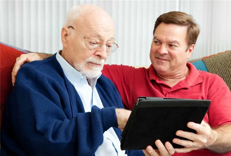 A man helping an elderly man on an ipad
