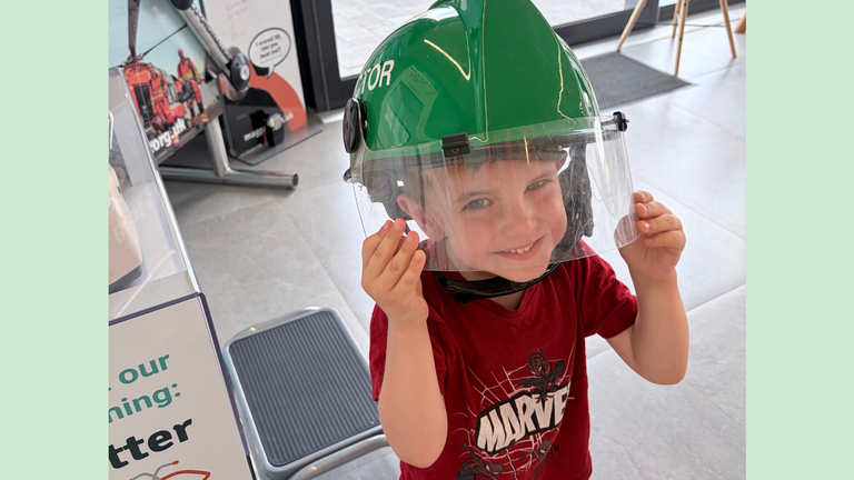 A little boy wearing a fireman's helmet and smiling at the camera