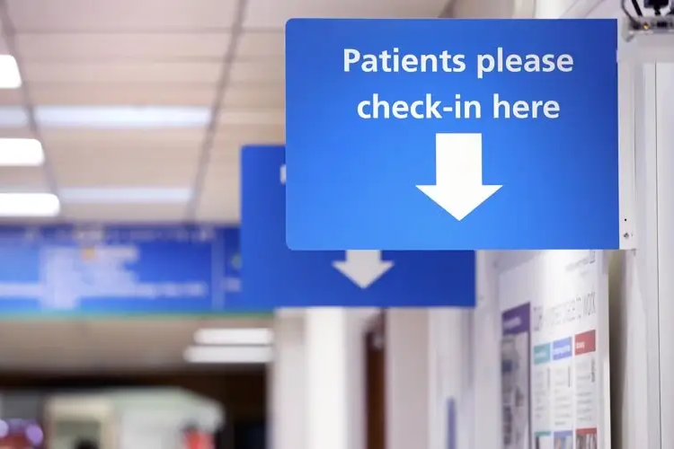 Patient check-in sign on wall in outpatients waiting area