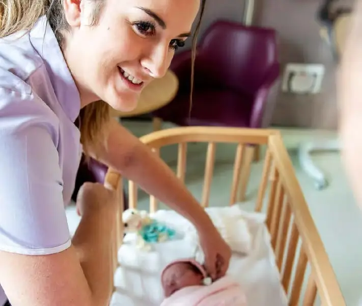 Midwife at the crib side of a newborn baby.