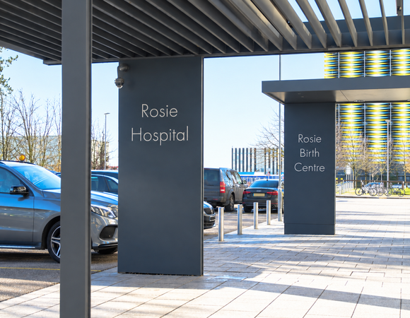Entrance to the Rosie Hospital, showign two dark grey pillars with the words 'Rosie Hospital' written on them.