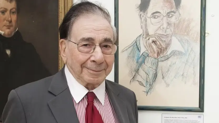 Sir Roy Calne standing next to a portrait of himself