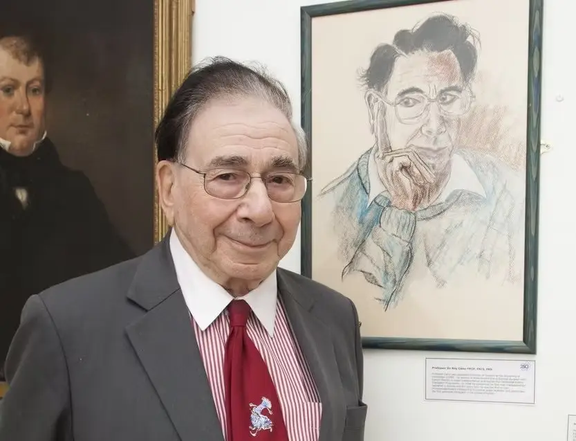 Sir Roy Calne standing next to a portrait of himself