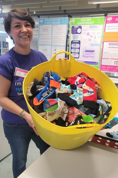 A woman holding a bucket filled with multi-coloured socks
