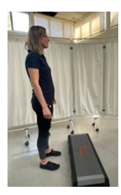 A woman standing in front of a step, feet hip width apart