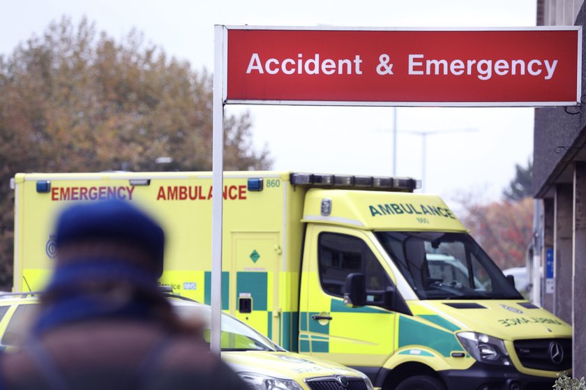 Photograph of an ambulance parked outside the Accident and Emergency Department with a person standing in the foreground.