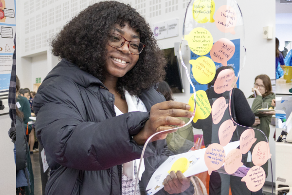 A woman smiling putting a post it note on a board